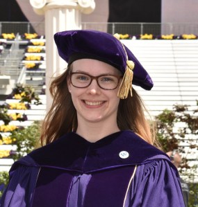 Rachael wearing the UW graduate regalia smiling.